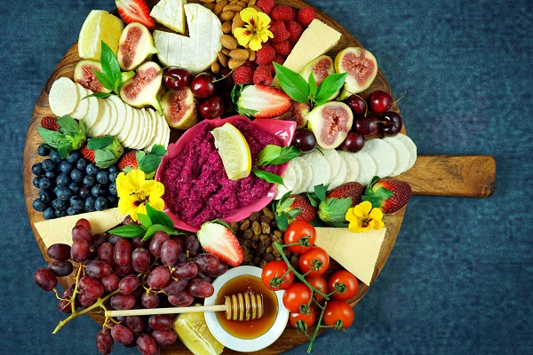 Cheese and fruit charcuterie dessert grazing platter on wooden board overhead.